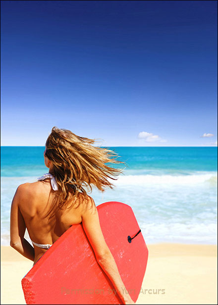 Blonde surfer girl walking toward the ocean with red boogie board under her arm